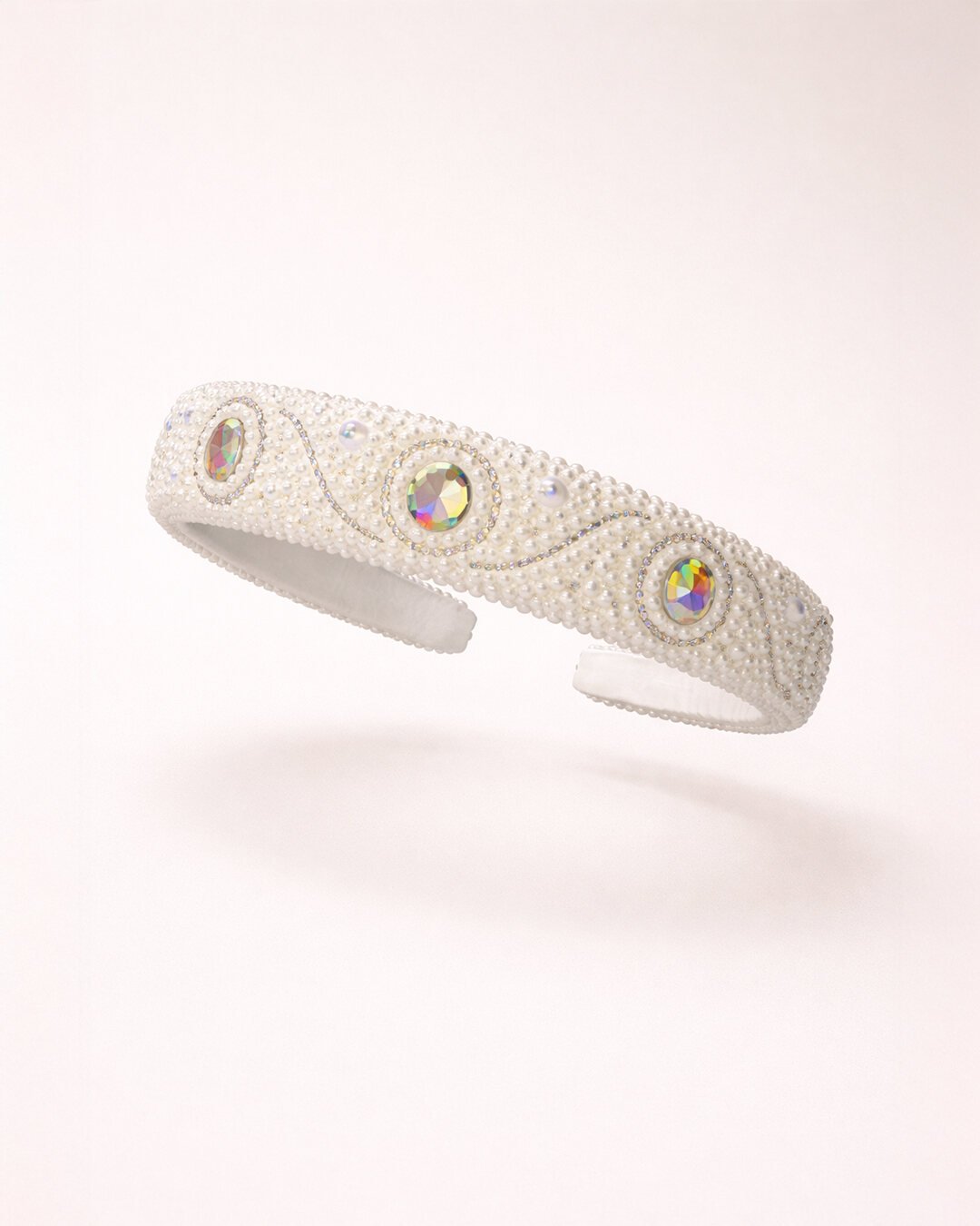 Pearl and crystal headband with oval iridescent stones, suspended against a pale ground