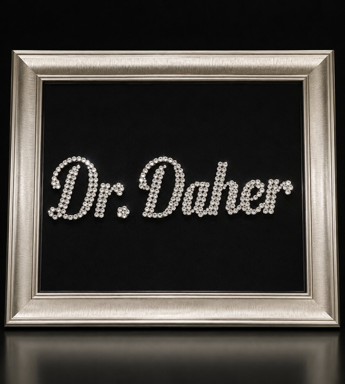 Framed crystal name work, clear crystals forming a script name on black velvet in a silver frame